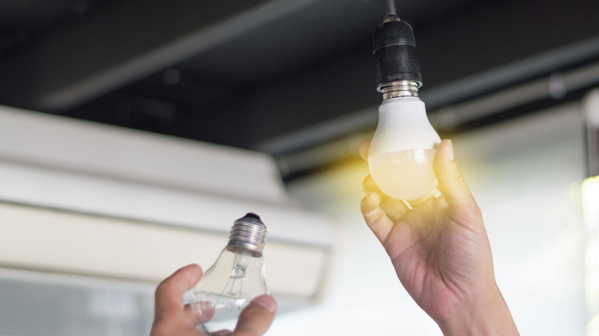 changing out a dead light bulb for a bright new light bulb connected to ceiling