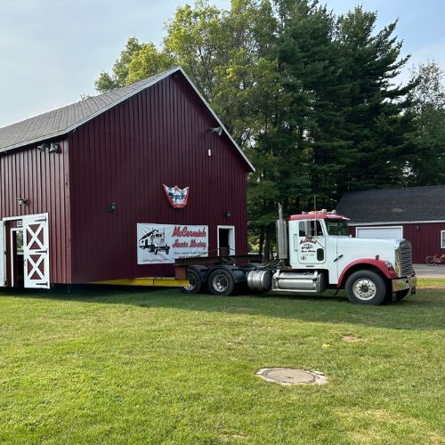 a truck hauling and moving a red barn