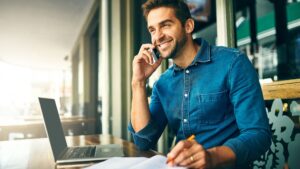 man talking on the phone in front of his laptop